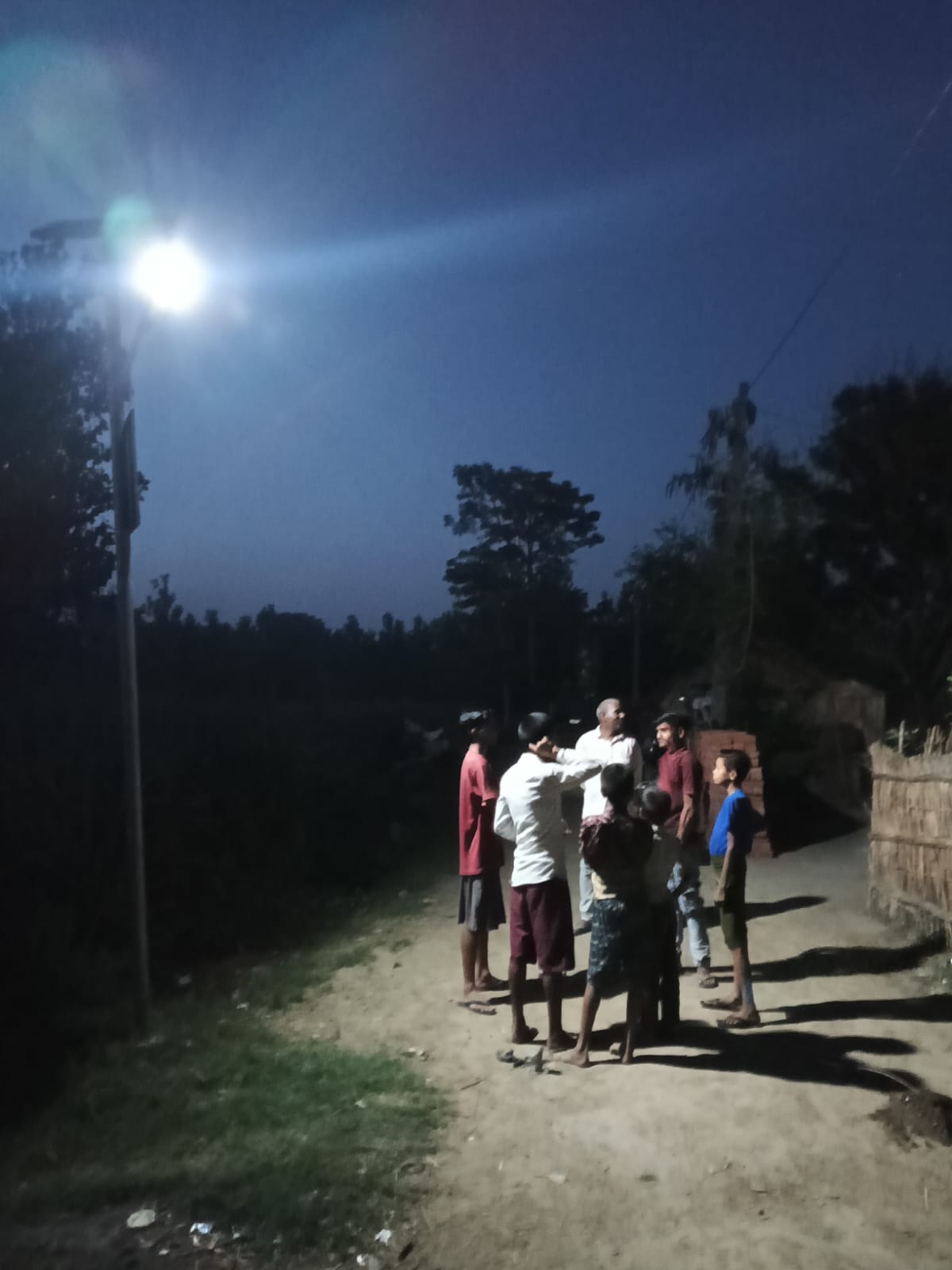A shopkeeper outside her village shop lit by a solar street light